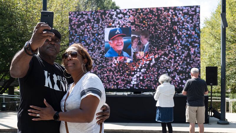 Kevin and Ursula Jones take a photo together in front of a video screen while attending the...