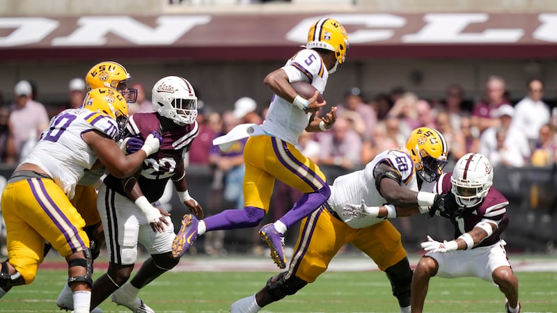 LSU quarterback Jayden Daniels (5) leaps into the air as he attempts to avoid a tackle by...